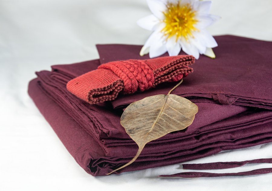 Folded robe cloth with a woven belt, a Bodhi leaf and a white water lily