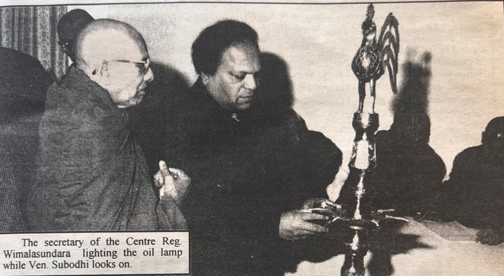 The secretary of the Centre, R. C. Wimalasundera, lighting the oil lamp while Venerable Subodhi looks on